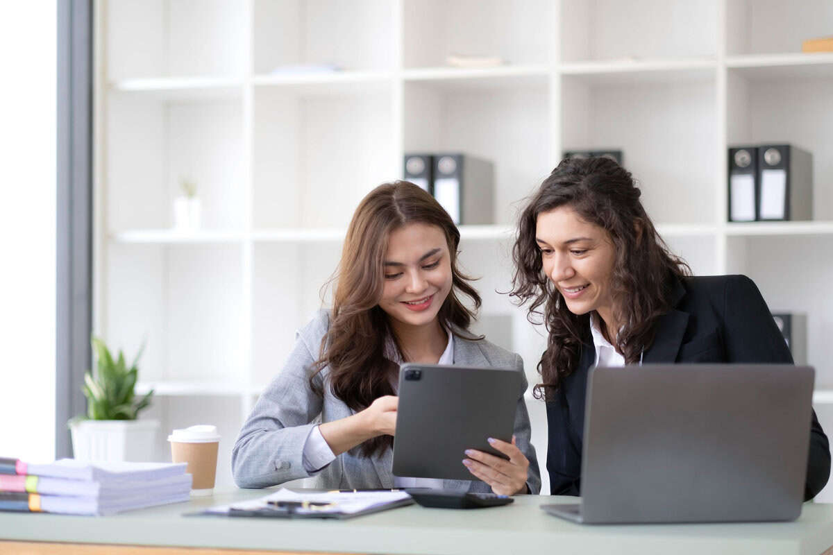 Two woman sitting and discussing with laptop and ipad testimonial